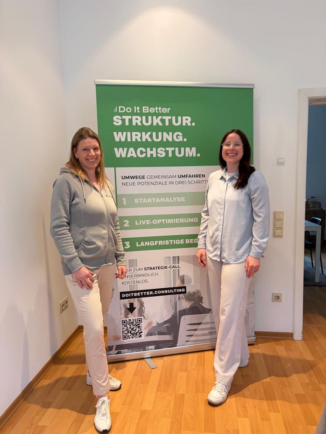 Zwei Teilnehmerinnen vor der Do-It-Better-Markenwand